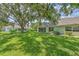 Lush green backyard with mature trees casting shadows on the well-manicured lawn for a serene outdoor space at 2309 Mooney. Pl, Sun City Center, FL 33573