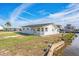 Waterfront home featuring a well-kept lawn, private water access, and classic architectural details under a partly cloudy sky at 3396 Minnow Creek Dr, Hernando Beach, FL 34607