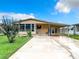Charming single Gathering home with a covered entry, open carport, and front yard with healthy green grass and landscaping at 35801 Verda Dr, Zephyrhills, FL 33541