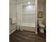 Modern bathroom with white tiled shower-tub, contemporary fixtures and hardwood-style flooring at 3763 Dartmouth N Ave, St Petersburg, FL 33713