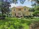 Charming two-story yellow home with a front porch, landscaped yard, and an American flag displayed at 6527 Stonington Dr, Tampa, FL 33647