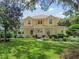 Two-story yellow house with wrap-around porch, landscaped yard, and American flag at 6527 Stonington Dr, Tampa, FL 33647