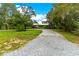 Landscaped yard with a gravel driveway leading to a charming house at 29249 Wilpayne Rd, Brooksville, FL 34602