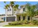 Two-story house with white siding, dark gray garage door, and lush landscaping at 807 W Kentucky Ave, Tampa, FL 33603