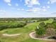 Aerial view of a golf course with lush greenery, a pond, and clear blue skies at 13102 Prestwick Dr, Riverview, FL 33579
