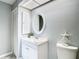 Well-lit bathroom with a white vanity, a starfish decoration, and a round mirror at 4844 Booth Bay Dr, New Port Richey, FL 34652