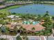 An aerial view of a community clubhouse, a swimming pool surrounded by palm trees, and lush landscaping at 5243 Esplanade Blvd, Bradenton, FL 34211