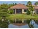 Charming home's backyard with water view, lush lawn, mature landscaping, and screened lanai at 5243 Esplanade Blvd, Bradenton, FL 34211