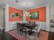 Dining room with an orange accent wall, white wainscoting, elegant lighting fixture, and a large picture window at 5243 Esplanade Blvd, Bradenton, FL 34211