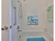 Clean bathroom with shower, tub, grab bars, and beach-themed art at 902 Mcdaniel St # 1, Sun City Center, FL 33573