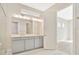 Elegant bathroom featuring double vanity with grey cabinets and a large mirror at 10520 Purple Thistle Way, San Antonio, FL 33576
