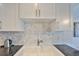 White kitchen cabinets and herringbone patterned backsplash at 4790 Snook Se Dr, St Petersburg, FL 33705