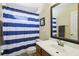 Clean bathroom with blue and white striped shower curtain and a vanity with a mirror at 7720 Rathdown Ln, Wesley Chapel, FL 33545