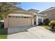 Tan house with red door, two car garage, and landscaped yard at 7720 Rathdown Ln, Wesley Chapel, FL 33545