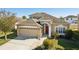 Two-story house with arched entryway, red door and a two-car garage at 7720 Rathdown Ln, Wesley Chapel, FL 33545