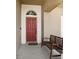 Red front door with arched window and welcoming bench at 7720 Rathdown Ln, Wesley Chapel, FL 33545