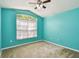 Teal bedroom with a ceiling fan and large window at 6843 Runner Oak Dr, Wesley Chapel, FL 33545