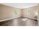 Empty bedroom with hardwood floors, baseboard trim, and two windows at 1109 Belcher Rd, Palm Harbor, FL 34683