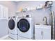 Modern laundry room featuring a sink with cabinet, shelving, front loading washer and dryer, and an ironing board at 2406 High Tides Way, Wesley Chapel, FL 33543