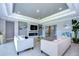Living room with tray ceilings, fireplace, large TV, tile floors, and two sofas at 2406 High Tides Way, Wesley Chapel, FL 33543