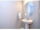 Powder room with pedestal sink, oval mirror, silver faucet, towel, and light fixture on a neutral wall at 2406 High Tides Way, Wesley Chapel, FL 33543