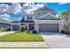Two-story house with gray siding, two-car garage, and landscaped lawn at 2406 High Tides Way, Wesley Chapel, FL 33543