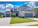 Two-story house with gray siding, two-car garage, and landscaped lawn at 2406 High Tides Way, Wesley Chapel, FL 33543