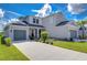 Two-story house with gray siding, two-car garage, and landscaped lawn at 2406 High Tides Way, Wesley Chapel, FL 33543