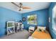 Blue bedroom with twin bed, workspace, and ceiling fan at 301 N Glen Ave, Tampa, FL 33609