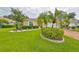 Landscaped front yard with lush lawn, palm trees, and well-manicured bushes at 736 Mccallister Ave, Sun City Center, FL 33573