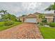 Tan one-story home with brick driveway and landscaping at 736 Mccallister Ave, Sun City Center, FL 33573