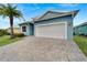 Front view of light blue home with white garage door and paver driveway at 567 Bimini Bay Blvd, Apollo Beach, FL 33572