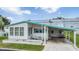 White single-wide home with teal accents and carport at 37743 Mission Hills Ave, Zephyrhills, FL 33541