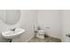 This bathroom features a pedestal sink, a white toilet, and neutral-toned tile flooring at 4265 Big Sky Dr, Spring Hill, FL 34604