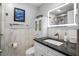Modern bathroom with a vanity featuring a black countertop, illuminated mirror, and tiled walls at 1819 Shore S Dr # 318, South Pasadena, FL 33707
