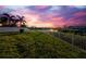 Beautiful waterfront view with a lush green lawn and white fence against a stunning pink and purple sunset at 6404 Key Island Ave, Apollo Beach, FL 33572