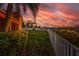 Landscaped backyard with a white fence overlooking a waterway at sunset at 6404 Key Island Ave, Apollo Beach, FL 33572