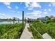Beautiful view of a long wooden private dock lined with lush greenery and calm waters in a waterfront community at 6404 Key Island Ave, Apollo Beach, FL 33572