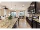 Bright kitchen featuring granite countertops, dark cabinets, stainless steel appliances, and an island with sink at 6404 Key Island Ave, Apollo Beach, FL 33572