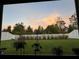 Landscaped backyard with a white picket fence and sunset view at 5776 Newberry Pines Ave, Wesley Chapel, FL 33545