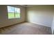 Neutral carpeted bedroom with a window allowing natural lighting and backyard view at 18146 Beach Ranch Ter, Lakewood Ranch, FL 34211