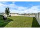 Well-maintained backyard with lush green grass, a white picket fence, and tranquil pond views at 10744 Hawks Landing Dr, Land O Lakes, FL 34638