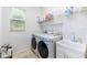 Bright laundry room with washer, dryer, utility sink, and shelving at 8945 Bella Vita Cir, Land O Lakes, FL 34637