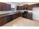 Well-lit kitchen featuring dark wood cabinetry, black appliances, and neutral countertops set on tiled flooring at 13292 Sea Bridge Dr, Hudson, FL 34669