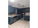 Modern kitchen with teal cabinets, stainless steel appliances, and tile flooring at 6115 7Th Ave, New Port Richey, FL 34653