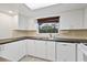 White kitchen with dark countertops, sink, dishwasher, and window at 1332 Maybury Dr, Holiday, FL 34691