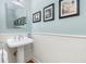 Powder room with pedestal sink, wainscoting, and decorative artwork at 1215 Bayshore Dr, Terra Ceia, FL 34250