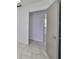 Hallway with neutral wall paint, gray tile floors, and an open door at 3908 W Wallace Ave, Tampa, FL 33611