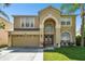 Two-story house with tan exterior, two-car garage, and nicely landscaped lawn at 5707 Butterfield St, Riverview, FL 33578