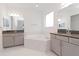 Bathroom with double vanity, corner tub, and gray cabinets at 10813 Rolling Moss Rd, Tampa, FL 33647
